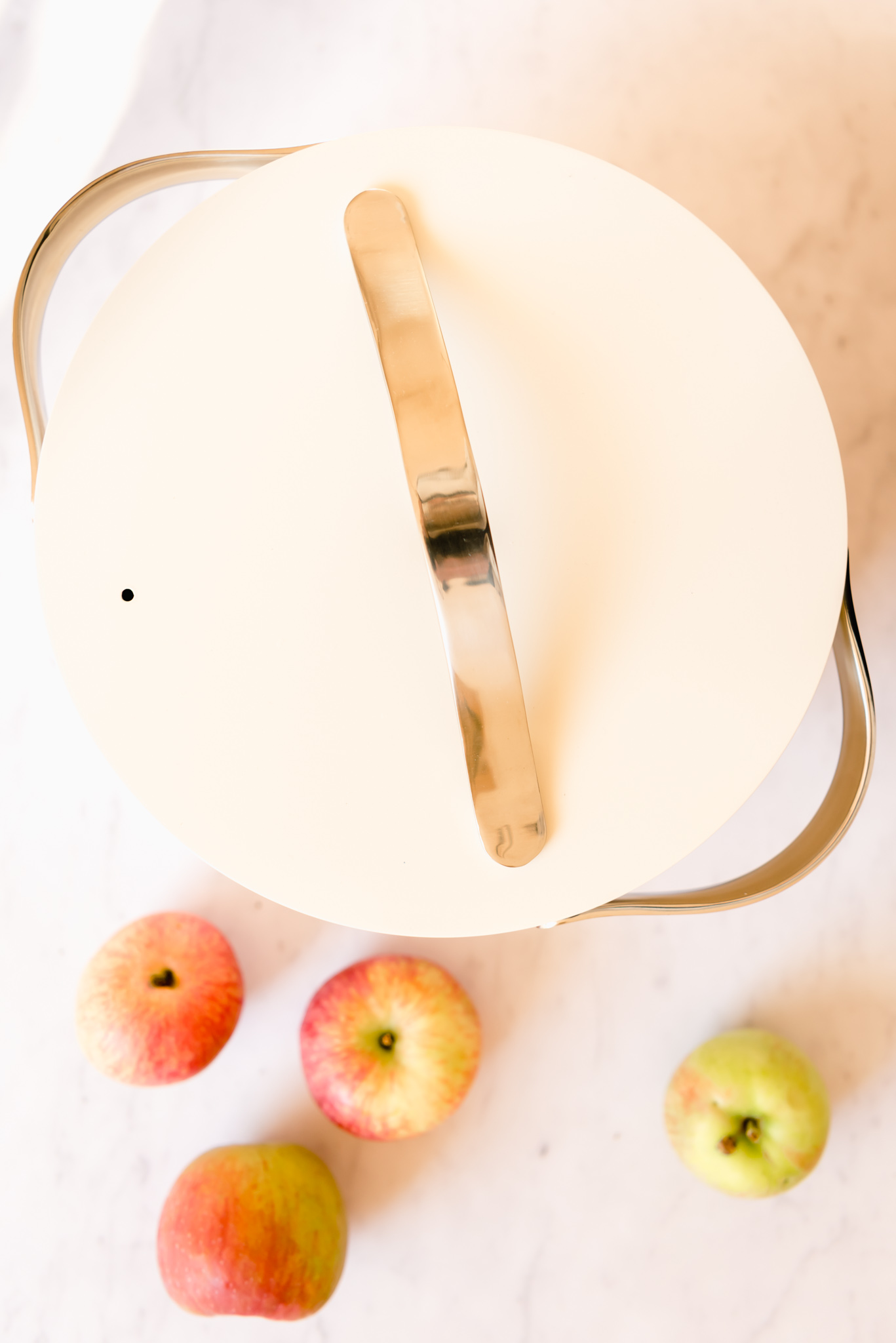 caraway dutch oven in cream with pink apples on a table